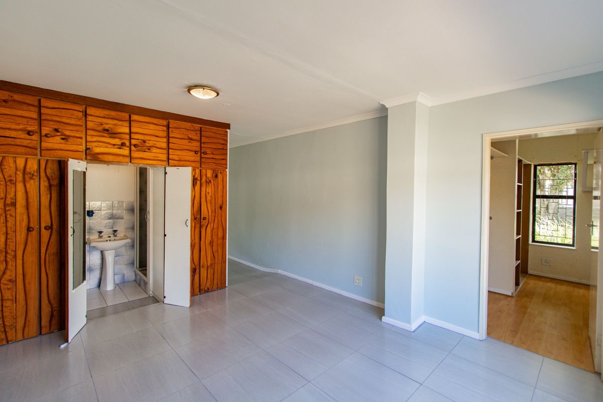 Bedroom featuring tiled flooring, built-in wooden cabinetry, and an en-suite bathroom, with an adjacent walk-in closet area.