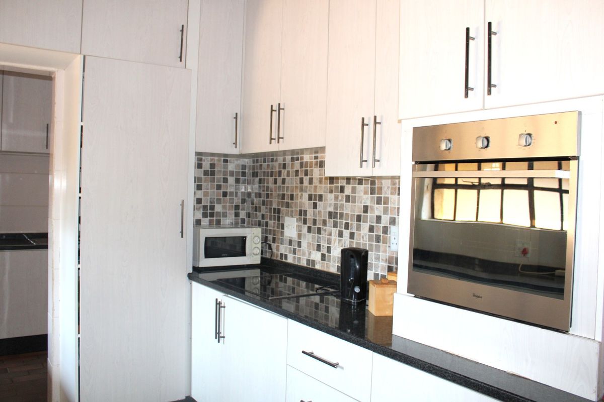Modern kitchen featuring white cabinetry, dark granite countertops, a mosaic tile backsplash, and a built-in stainless steel oven.