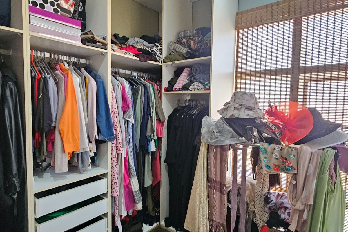 A walk-in closet featuring built-in floor-to-ceiling cabinetry with hanging rails, shelving, and integrated drawers.