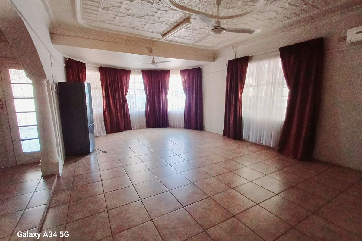 Spacious living area featuring decorative pressed metal ceilings, tiled flooring, and large windows with curtain treatments.