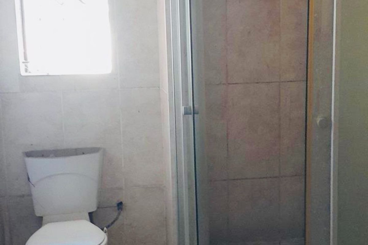 A compact bathroom featuring a corner shower enclosure with a glass door and a standard white toilet.