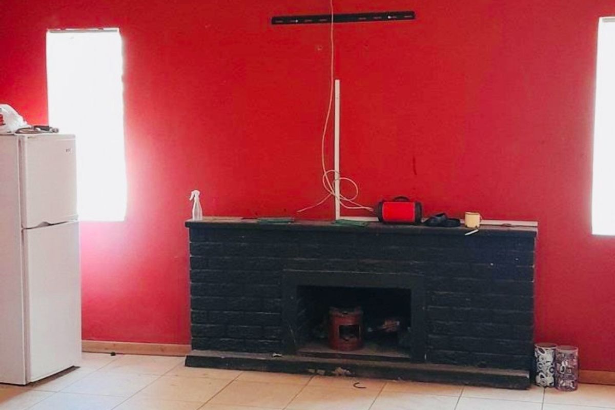 Living room featuring a brick fireplace, tiled flooring, and bright red accent walls with exposed wiring.