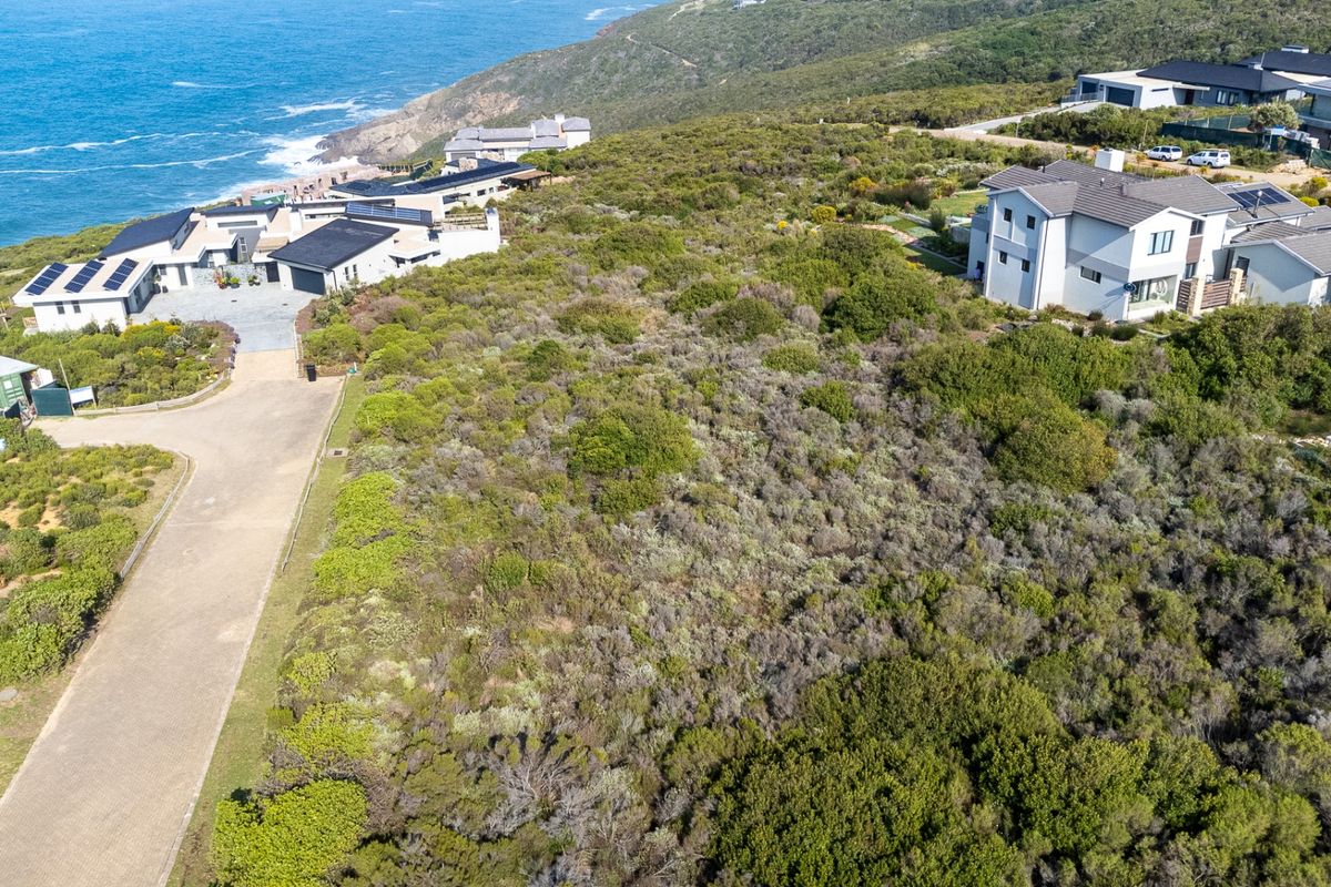 Aerial view of a vacant residential plot featuring natural coastal vegetation, situated in a developed estate with ocean views.