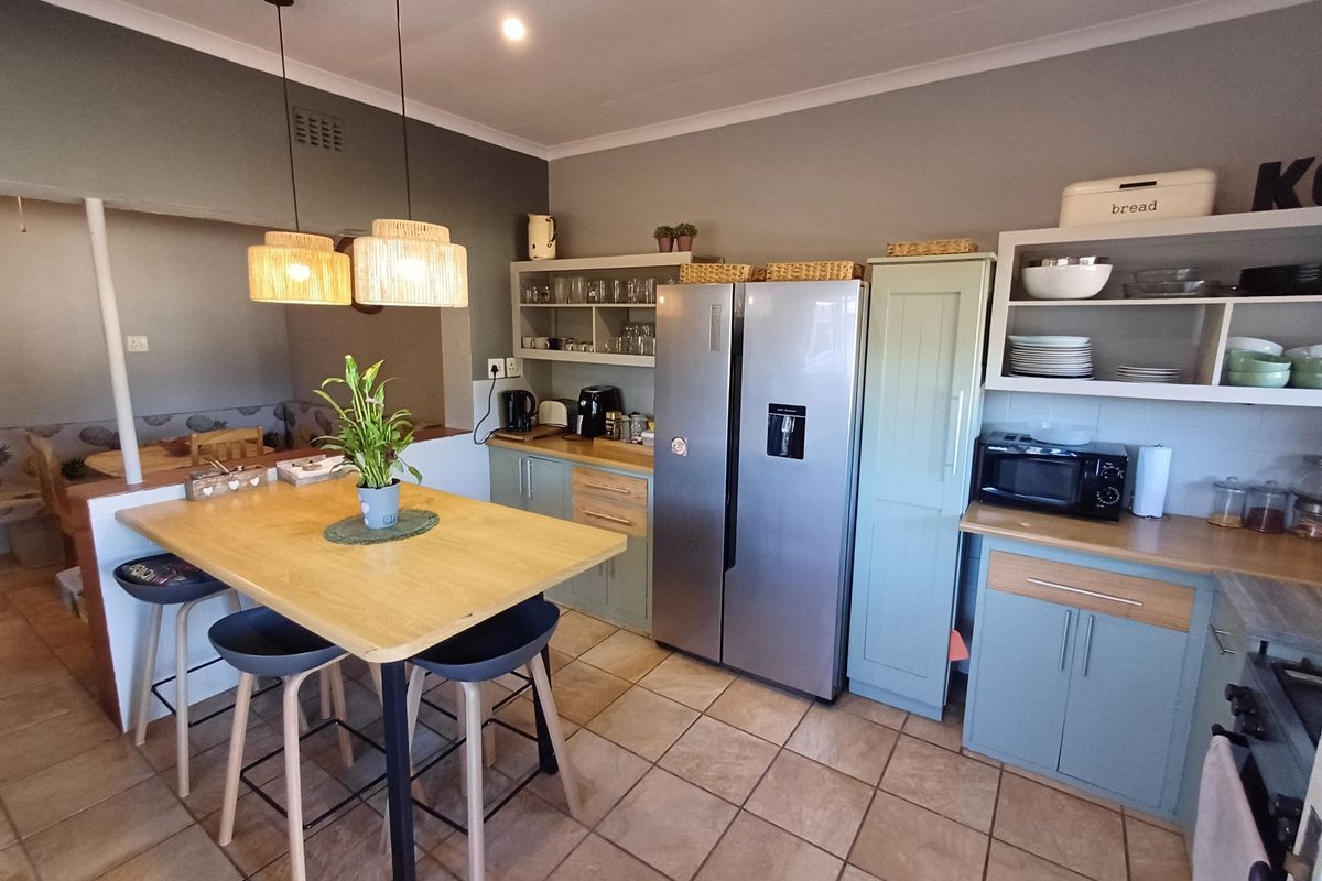 A functional kitchen featuring light blue cabinetry, wooden countertops, a built-in oven, and a central breakfast island with pendant lighting.
