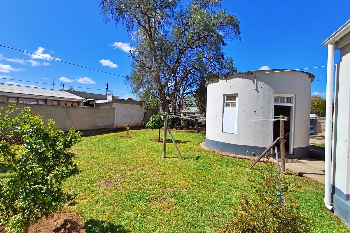 A spacious rear garden featuring a unique circular outbuilding, established lawn, and perimeter boundary walls.