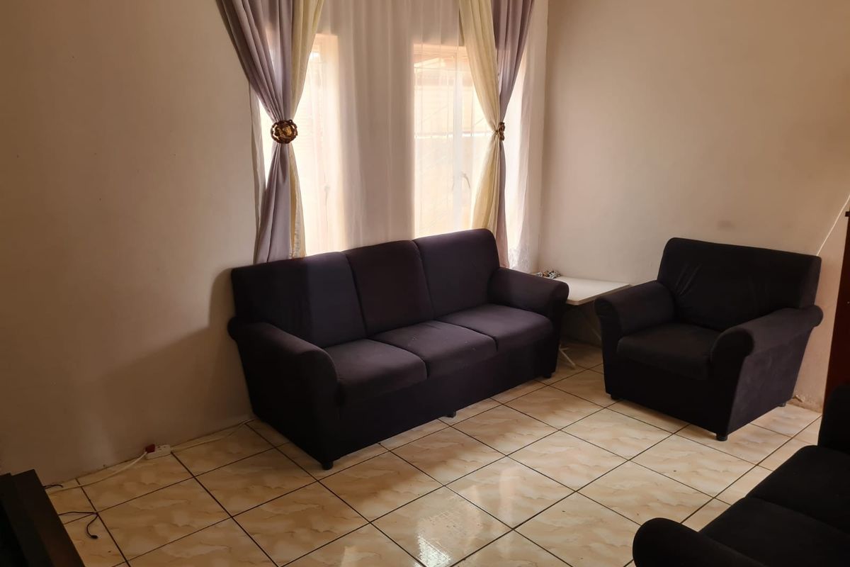 A living room featuring tiled flooring and dual windows with curtains, providing a functional and neutral space for relaxation.