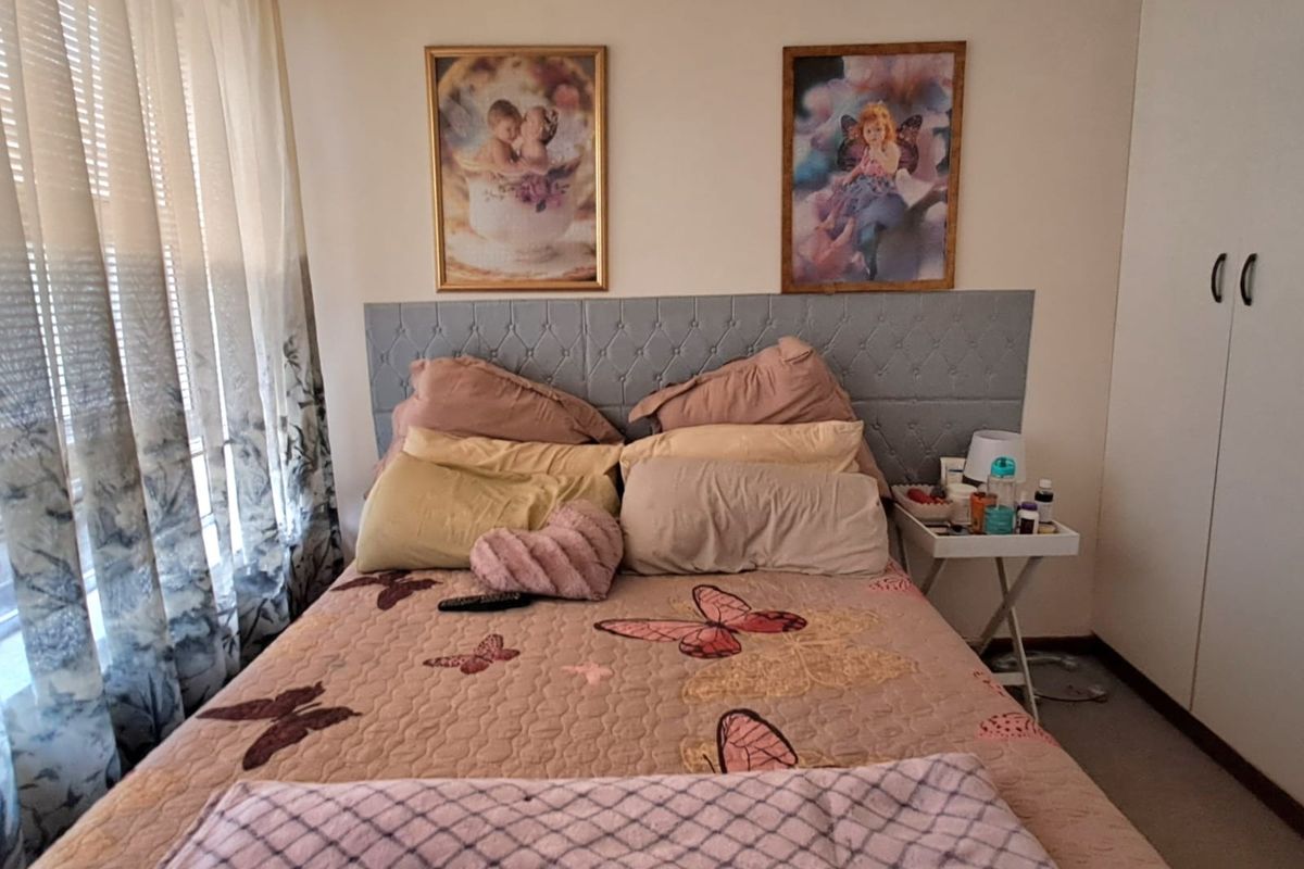 A bedroom featuring built-in cupboards and a padded headboard, offering a functional space with natural light from the window.