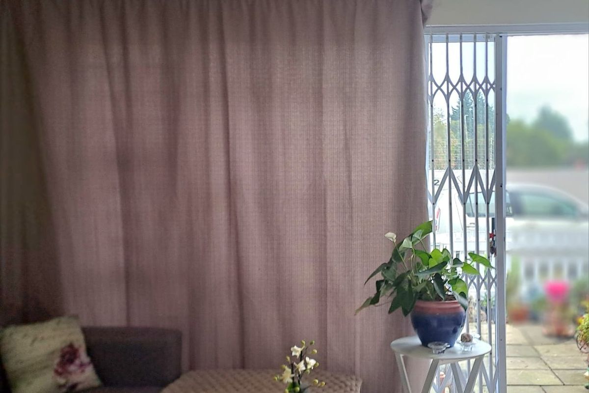 Living room area featuring tiled flooring and a sliding glass door with a security gate leading to an outdoor patio.