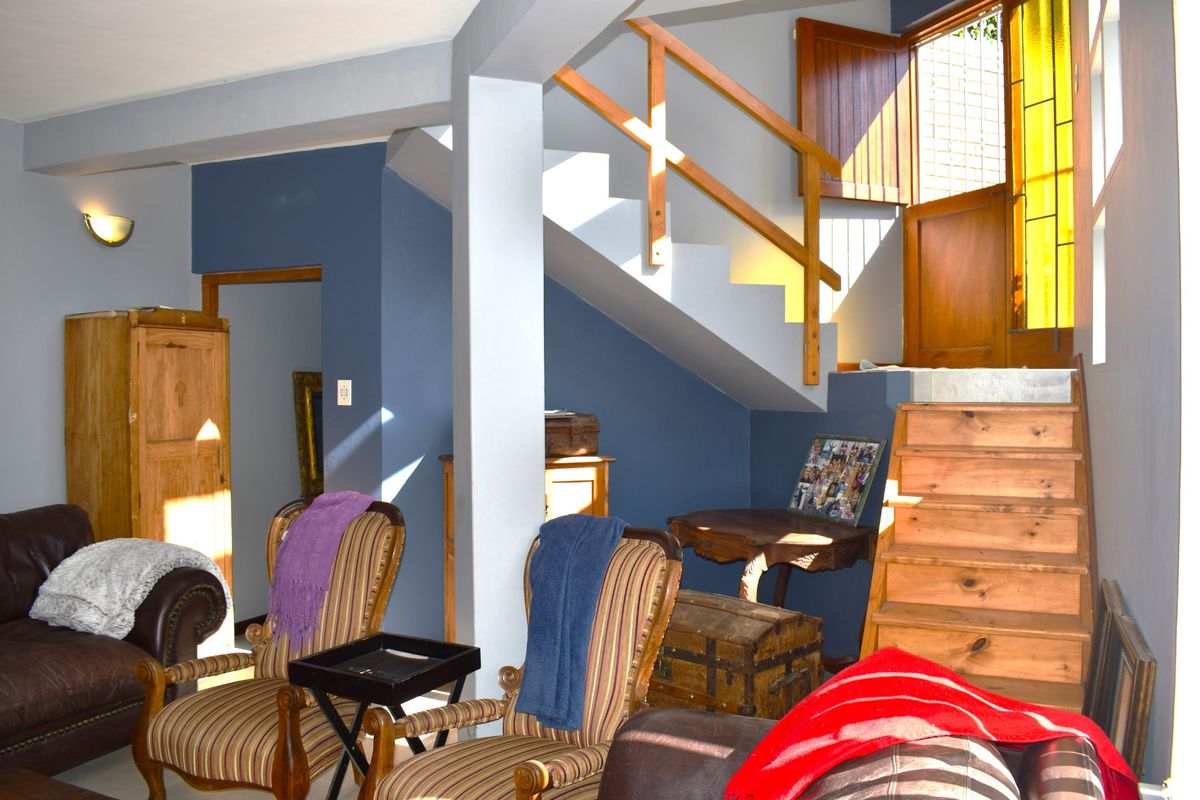 A living area featuring a wooden staircase with a timber handrail, leading to an exterior door with stained glass accents.