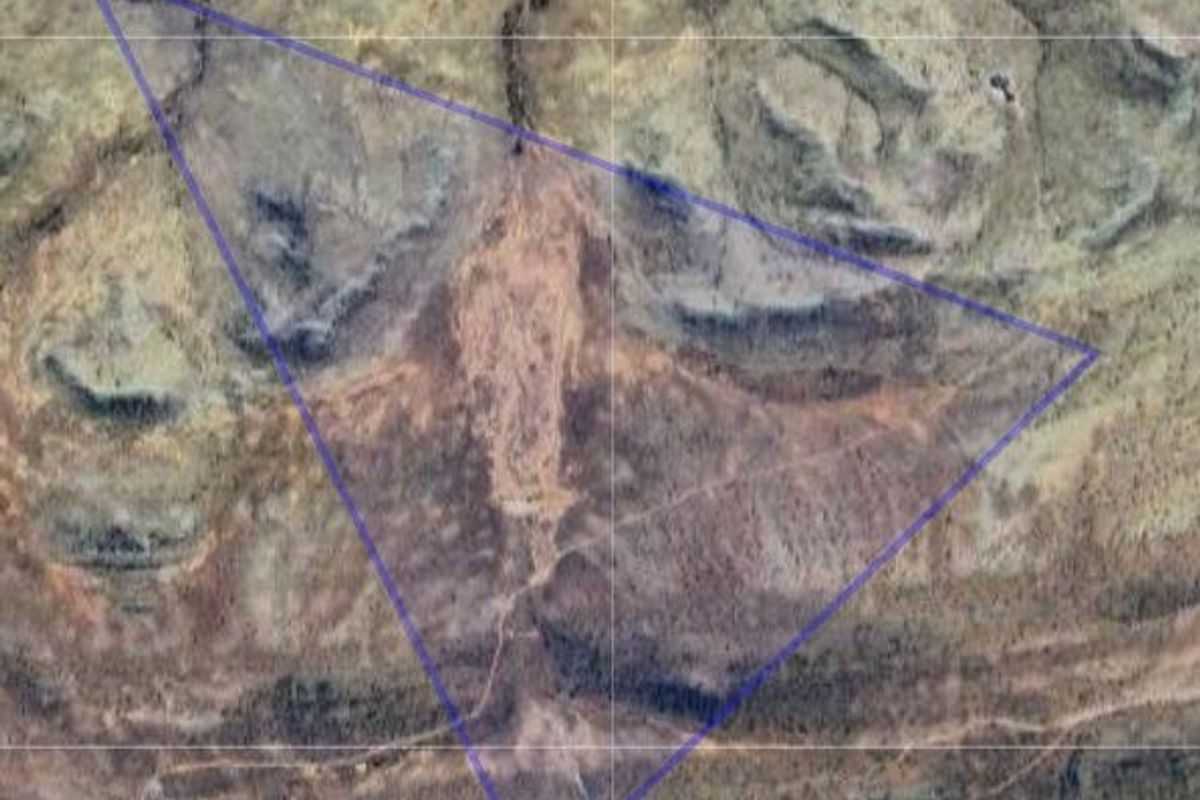 An aerial view of a vacant residential land plot, highlighting the natural terrain and boundaries of the property.