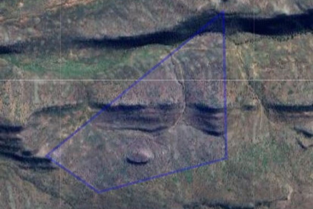An aerial view of a vacant residential land parcel, highlighting the natural topography and boundaries of the property.