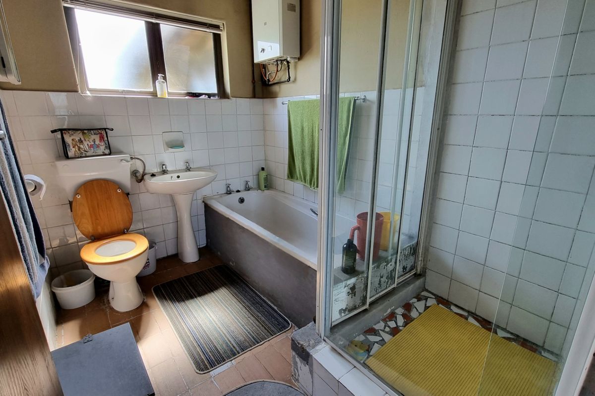A functional bathroom featuring a pedestal basin, bathtub, and separate shower enclosure with tiled walls and flooring.