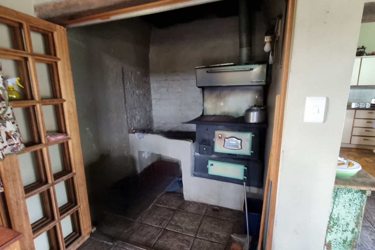 A rustic kitchen alcove featuring a vintage built-in wood-burning stove and masonry hearth, adjacent to the main kitchen area.
