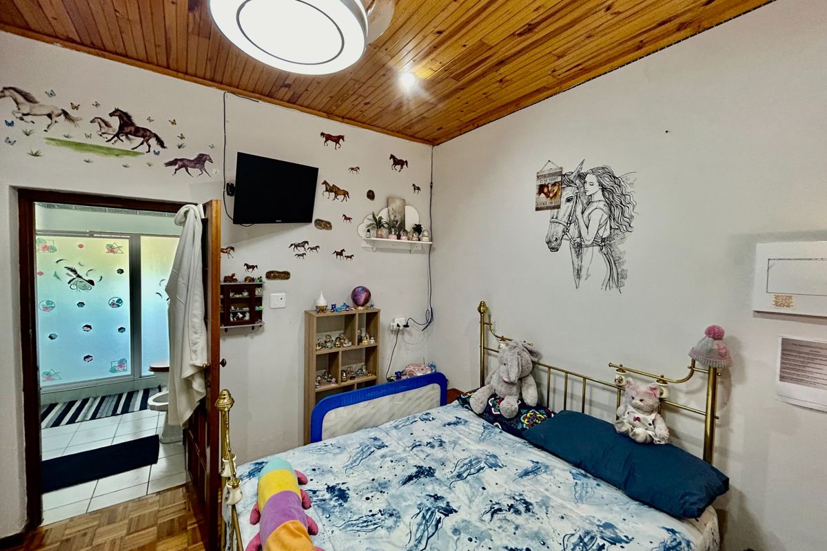 A bedroom featuring a wooden tongue-and-groove ceiling, parquet flooring, and an en-suite bathroom access.