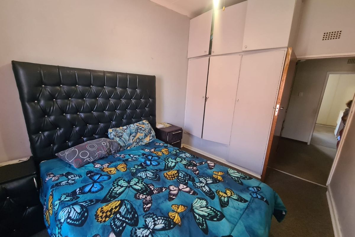 A bedroom featuring built-in floor-to-ceiling cupboards and carpeted flooring, providing functional storage space within the apartment.