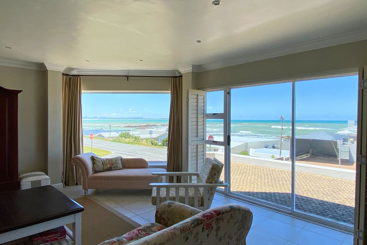 Spacious living area featuring large windows and sliding glass doors that offer expansive ocean views and direct access to an outdoor patio.