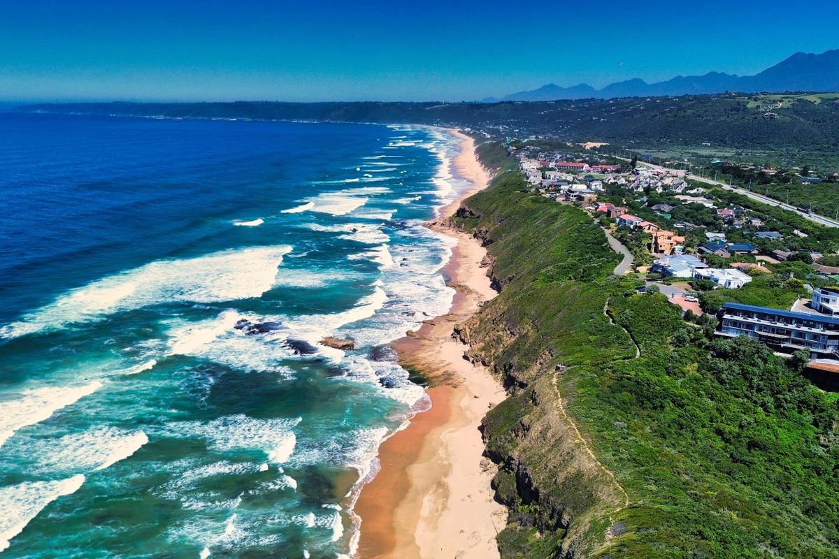An expansive aerial view of the coastline, showcasing the beach, ocean, and surrounding residential landscape.