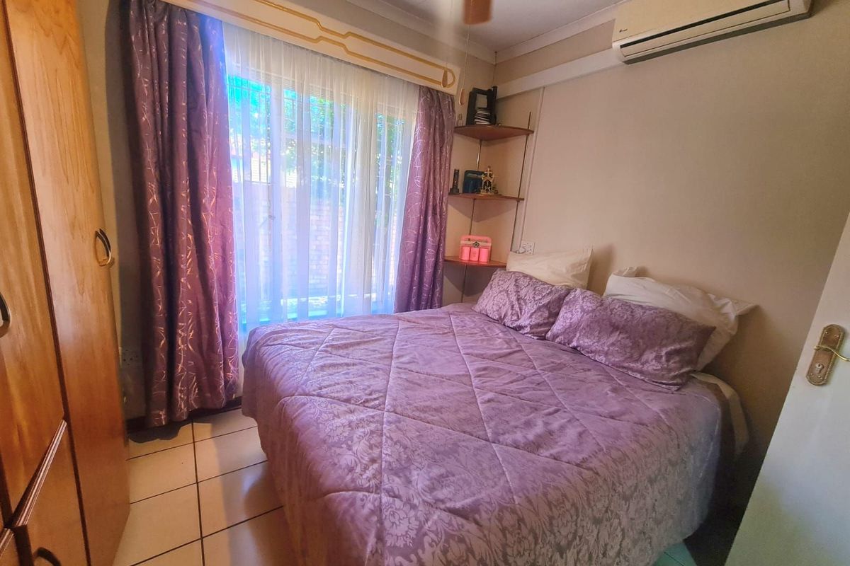 A cozy bedroom featuring tiled flooring, built-in wooden cabinetry, and a wall-mounted air conditioning unit.