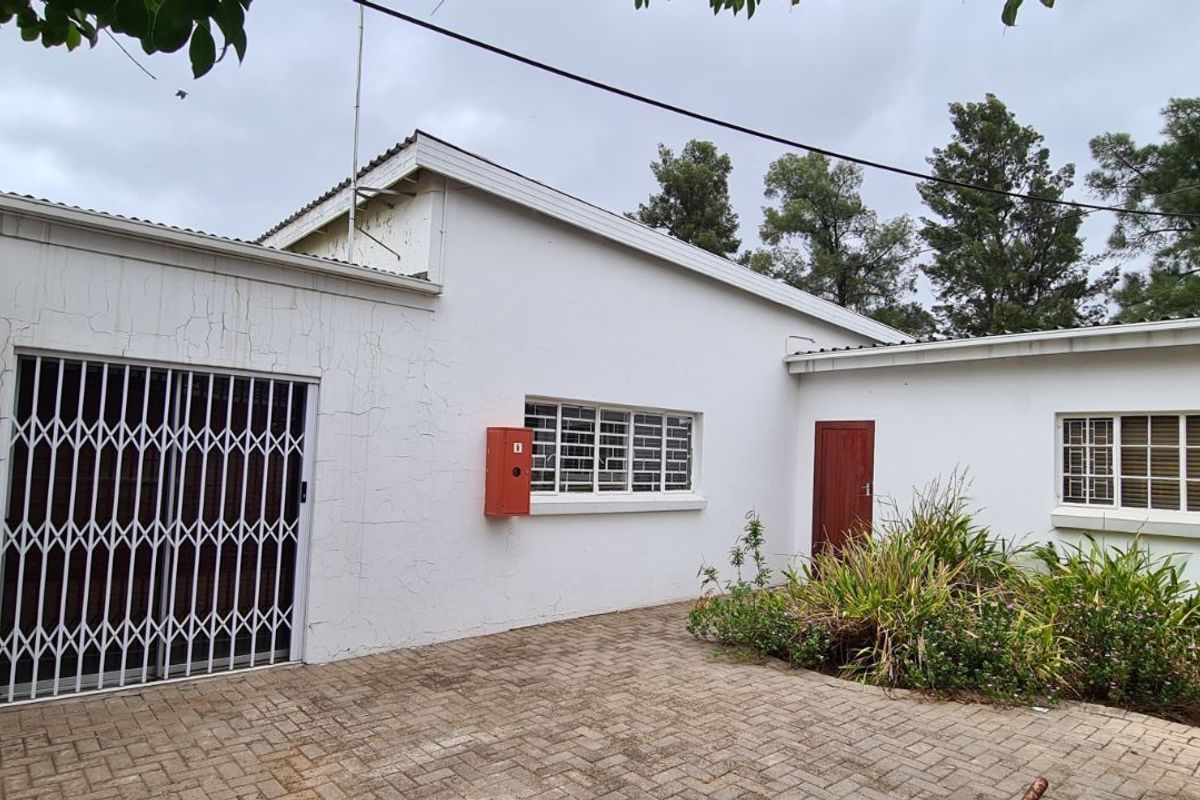 Exterior view of the office building featuring paved courtyard, security gates, and wall-mounted air conditioning unit.