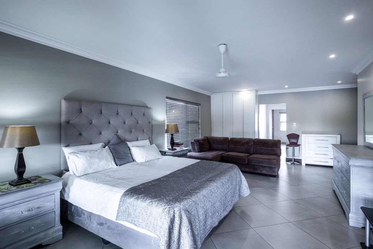 Spacious bedroom featuring tiled flooring, built-in cupboards, recessed ceiling lighting, and a ceiling fan.