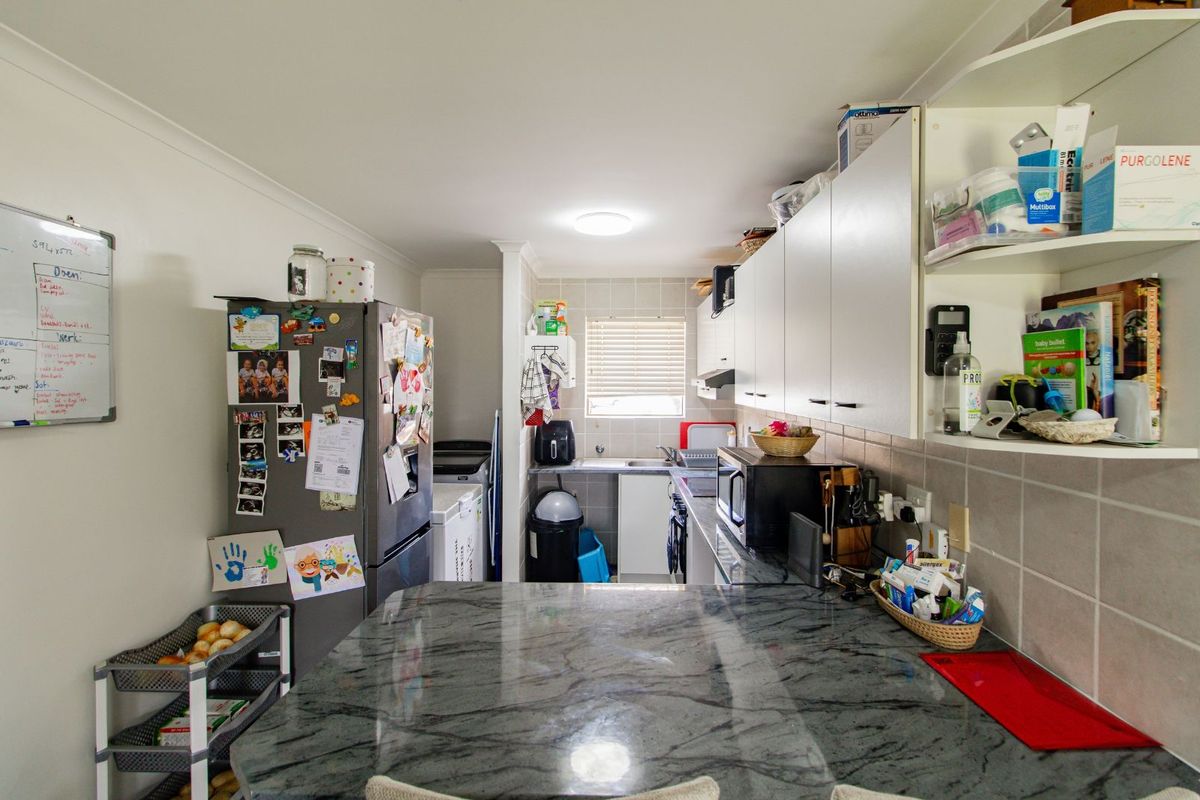 A functional kitchen featuring granite countertops, white cabinetry, and a tiled splashback, providing a practical workspace for daily meal preparation.