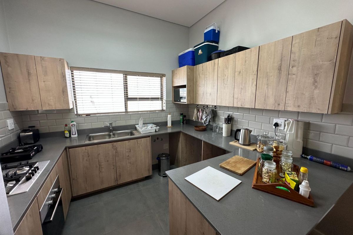 Modern kitchen featuring light wood-grain cabinetry, grey stone countertops, subway tile backsplash, integrated oven, and gas hob.