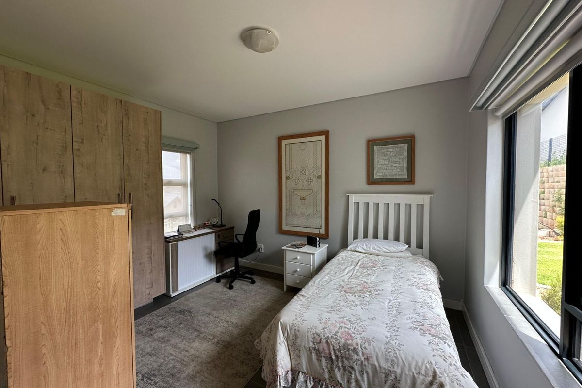 A well-maintained bedroom featuring built-in wooden cabinetry, large windows providing natural light, and neutral wall finishes.