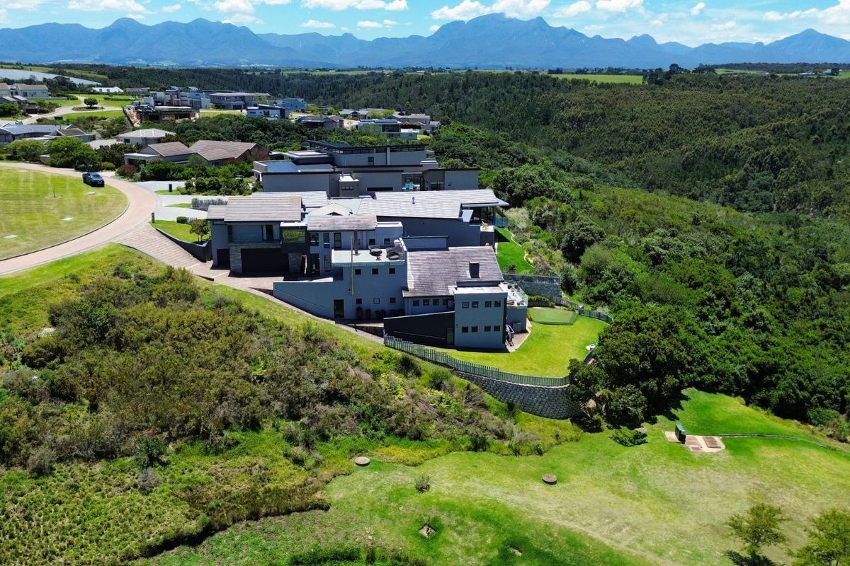 Aerial view of a modern residential property situated in a scenic estate, featuring landscaped grounds and expansive mountain views.