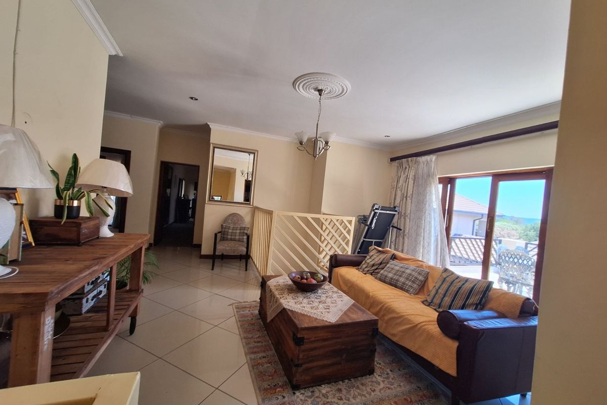 Spacious living area featuring tiled flooring, decorative ceiling rose, and sliding glass doors providing access to an outdoor balcony.