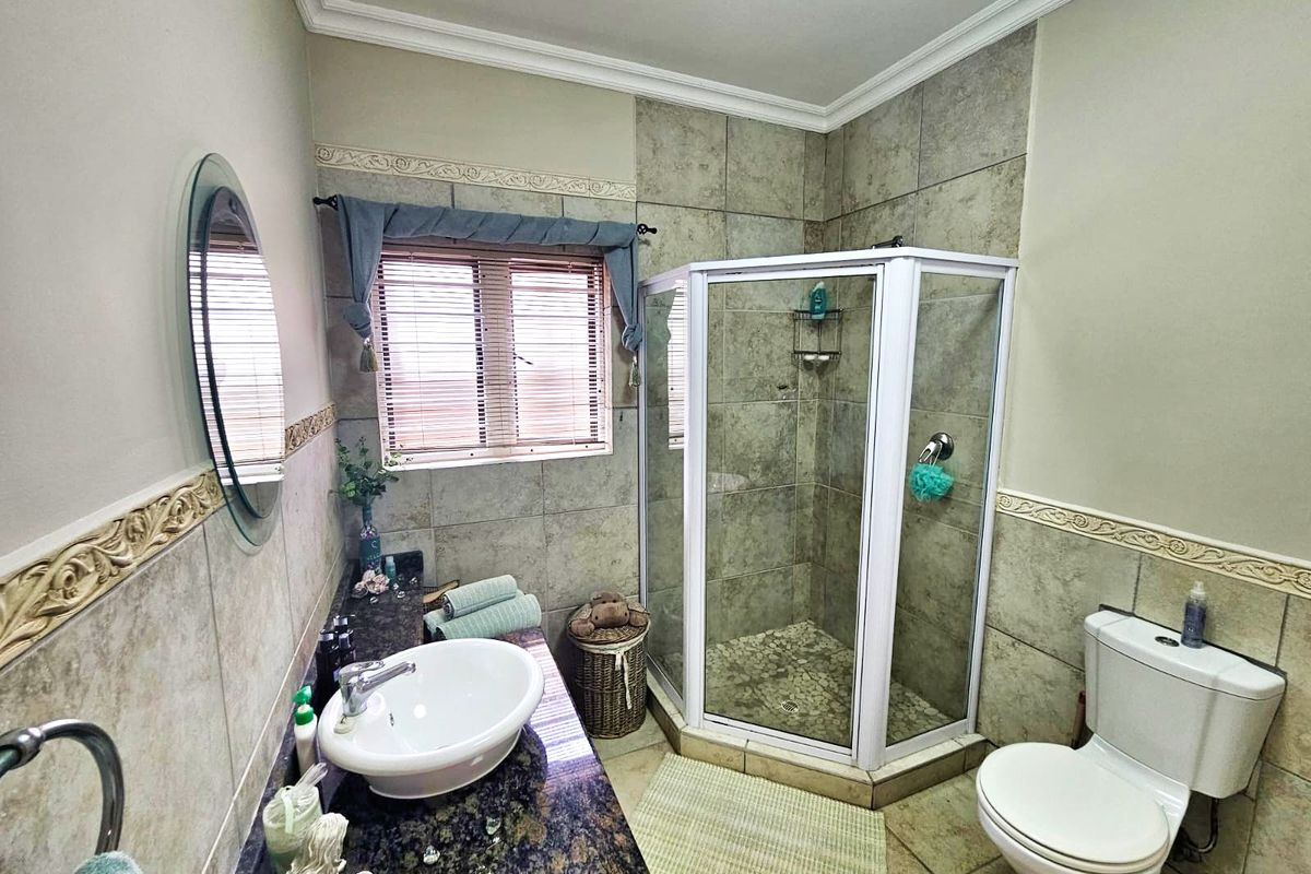 A functional bathroom featuring a corner shower enclosure, a vanity with a stone countertop, and a ceramic basin.