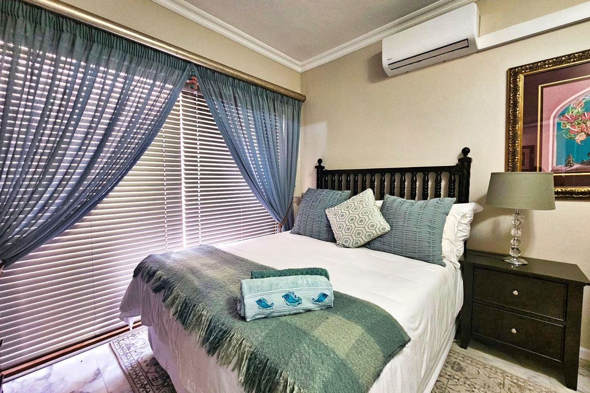A well-maintained bedroom featuring marble-style flooring, a wall-mounted air conditioning unit, and large sliding glass doors with integrated blinds.