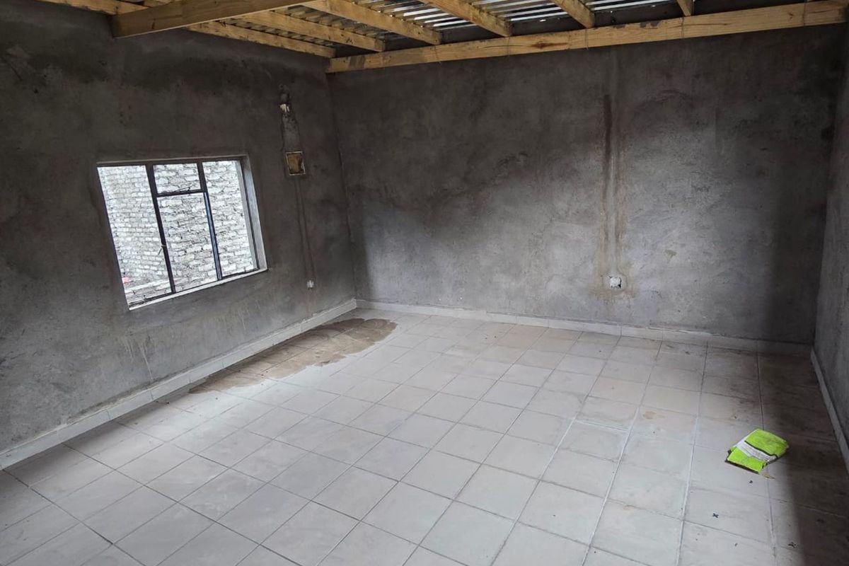 An unfinished interior room featuring tiled flooring, exposed timber roof beams, and raw plaster walls, offering a blank canvas for renovation.