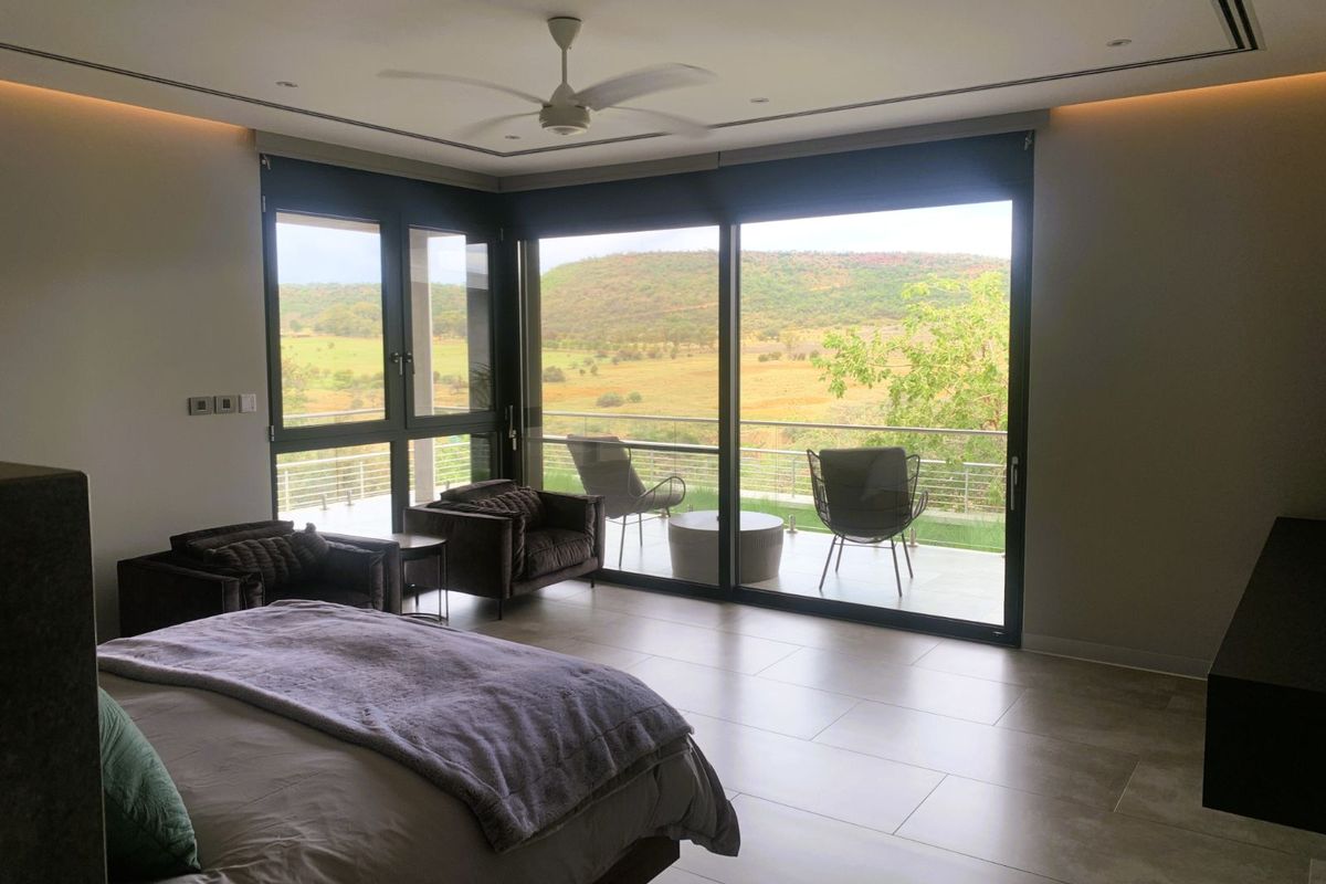 Spacious bedroom featuring large sliding glass doors that open onto a private balcony with expansive rural landscape views.