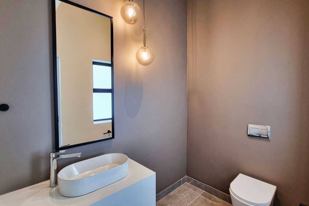 Modern guest bathroom featuring a sleek vessel sink, wall-mounted vanity, and a concealed cistern toilet with contemporary pendant lighting.