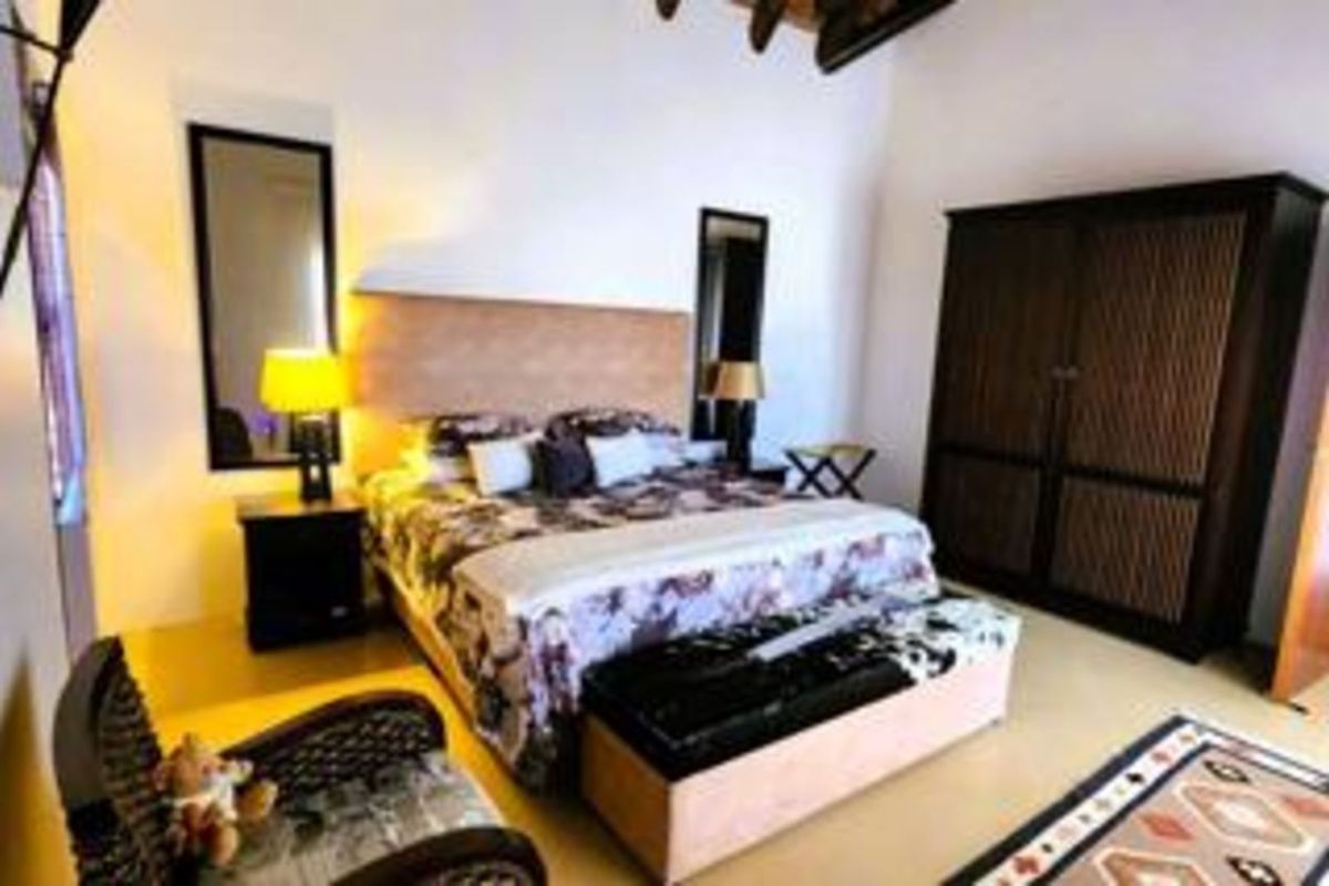 A spacious bedroom featuring high vaulted ceilings with exposed timber beams and built-in cabinetry.