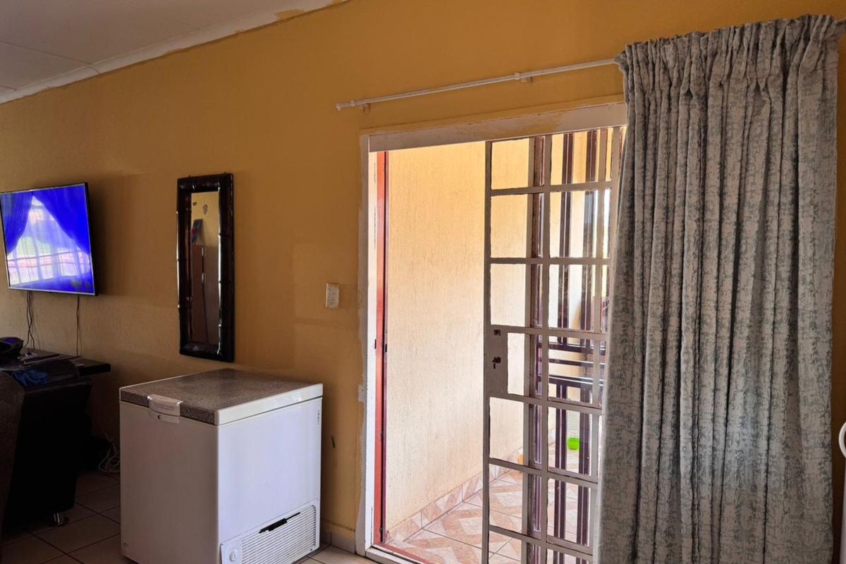 Living area featuring tiled flooring and a sliding door with security gate leading to an outdoor patio space.