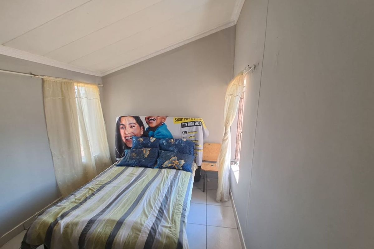 A bedroom featuring tiled flooring, a raked ceiling, and dual windows with natural light.