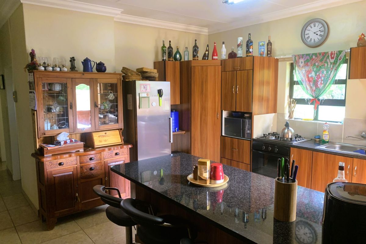 A functional kitchen featuring wood-toned cabinetry, a dark granite-topped island, built-in oven, and hob, providing a practical workspace for daily cooking.