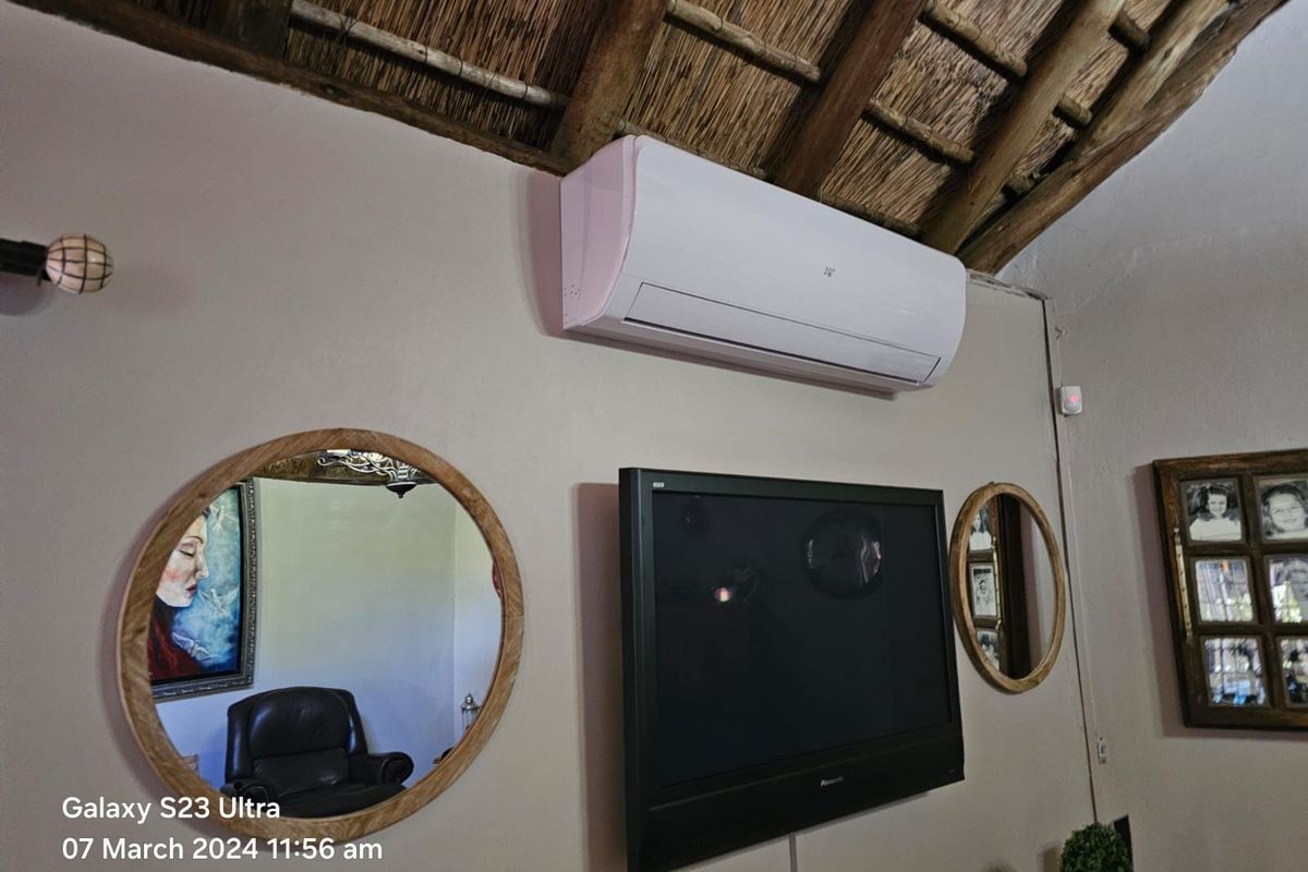 A living area featuring a traditional exposed thatch roof and a wall-mounted air conditioning unit.