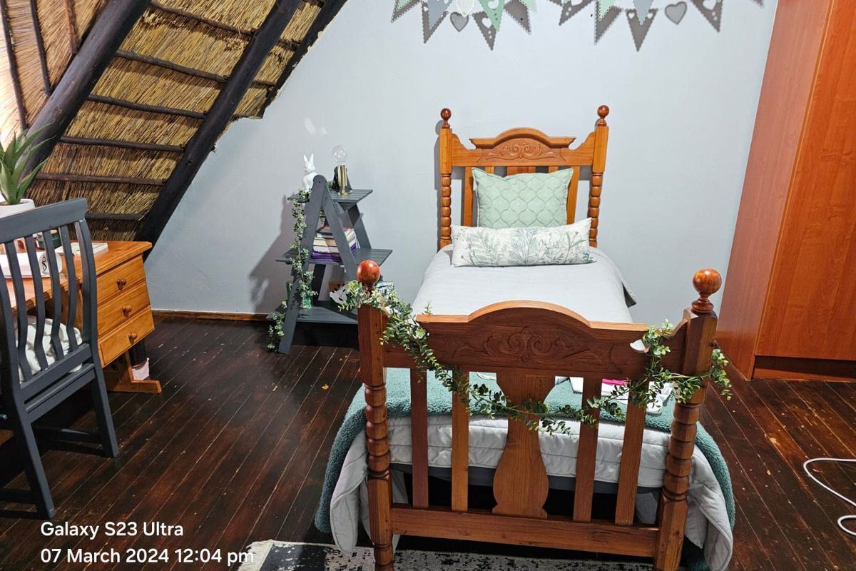 A cozy bedroom featuring a distinctive thatched roof ceiling, dark timber flooring, and a warm, rustic atmosphere.