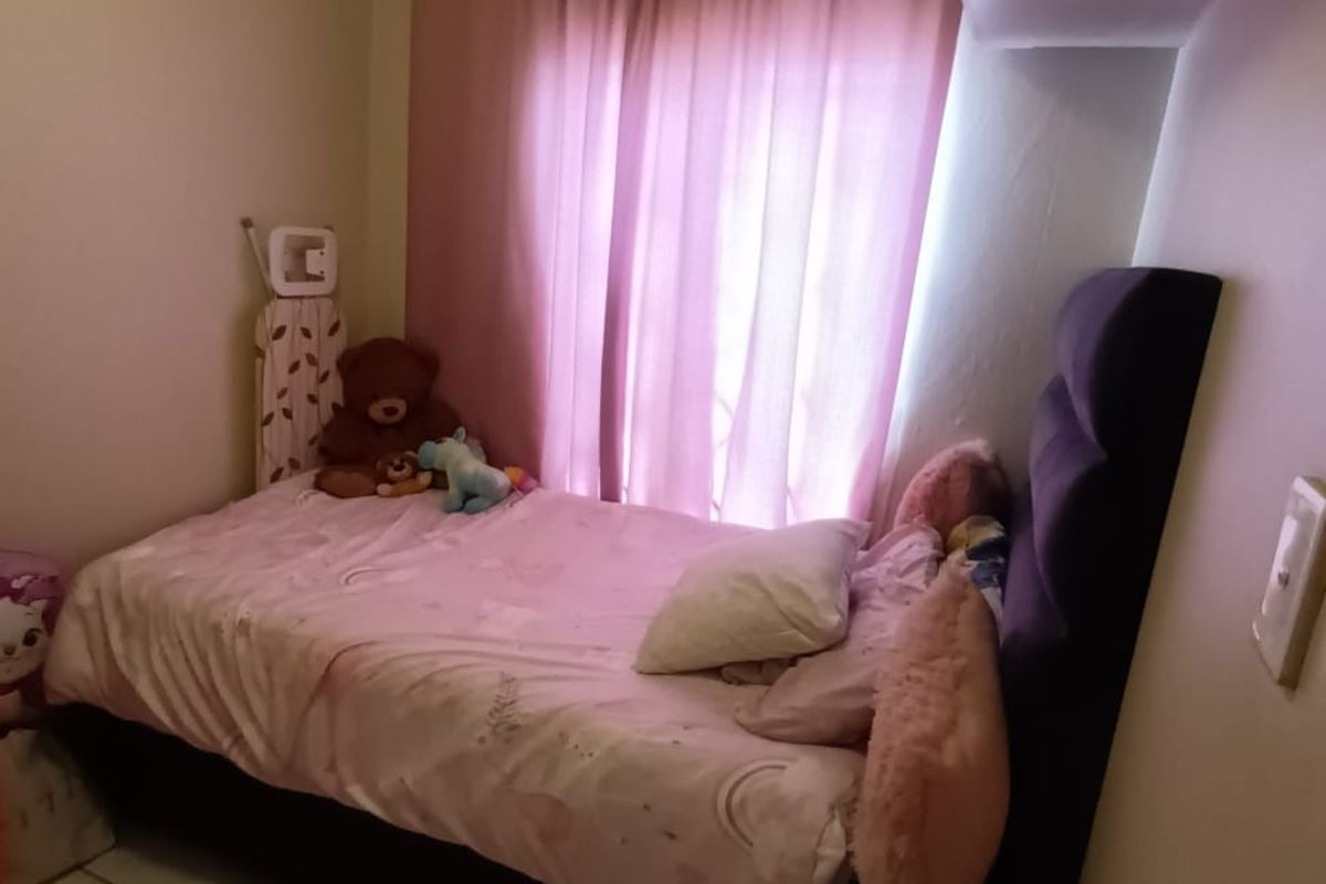 A compact bedroom featuring tiled flooring and a window with curtain treatments.