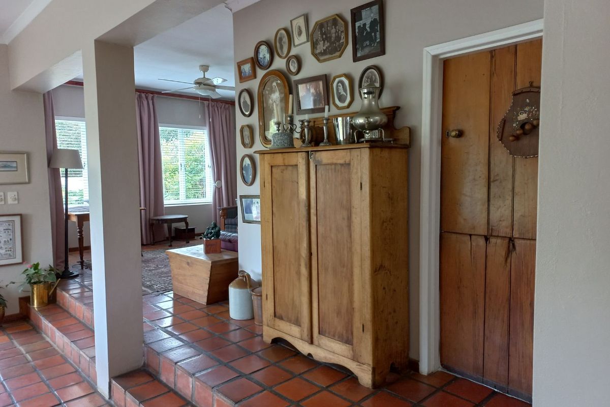 A view of a living area featuring terracotta floor tiles, a raised step transition, and a solid timber door leading to an adjacent room.
