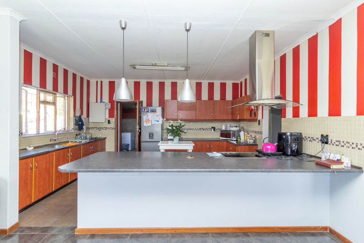 Spacious kitchen featuring a large central island, built-in cabinetry, stainless steel extractor fan, and tiled flooring.