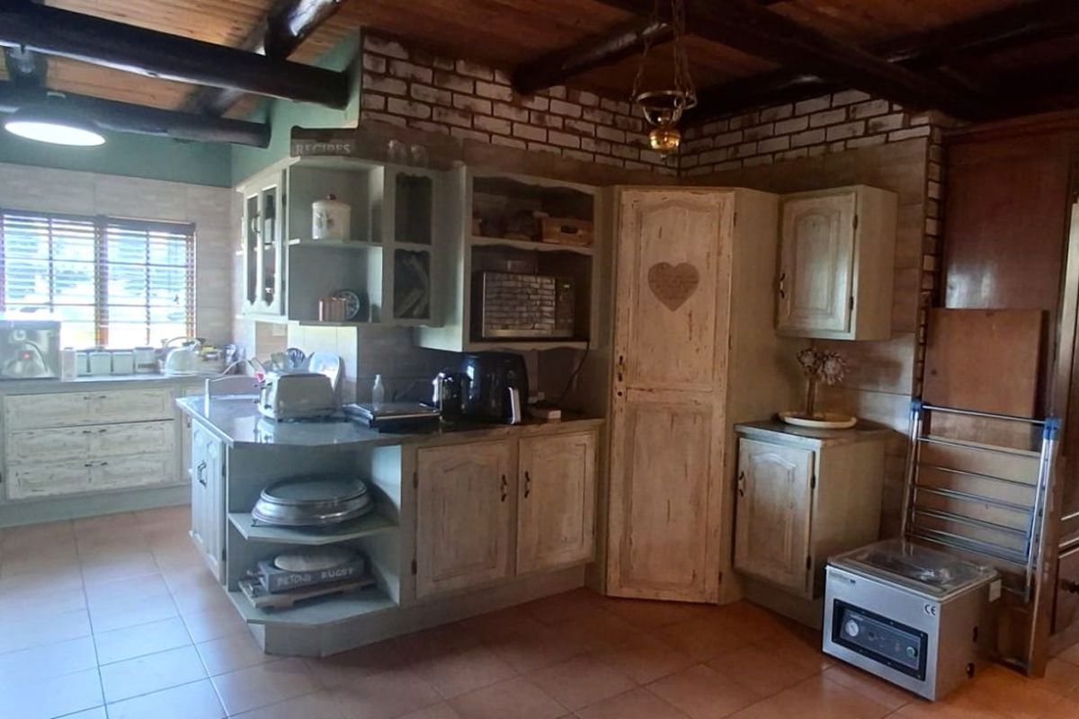 Rustic-style kitchen featuring exposed timber ceiling beams, brick accent walls, custom cabinetry, and tiled flooring in a warm, traditional aesthetic.