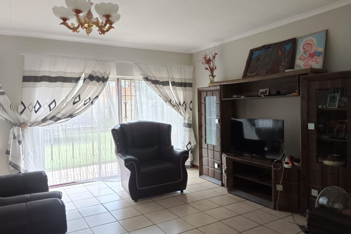 A living room featuring tiled flooring, a ceiling-mounted light fixture, and large sliding glass doors providing access to the exterior.
