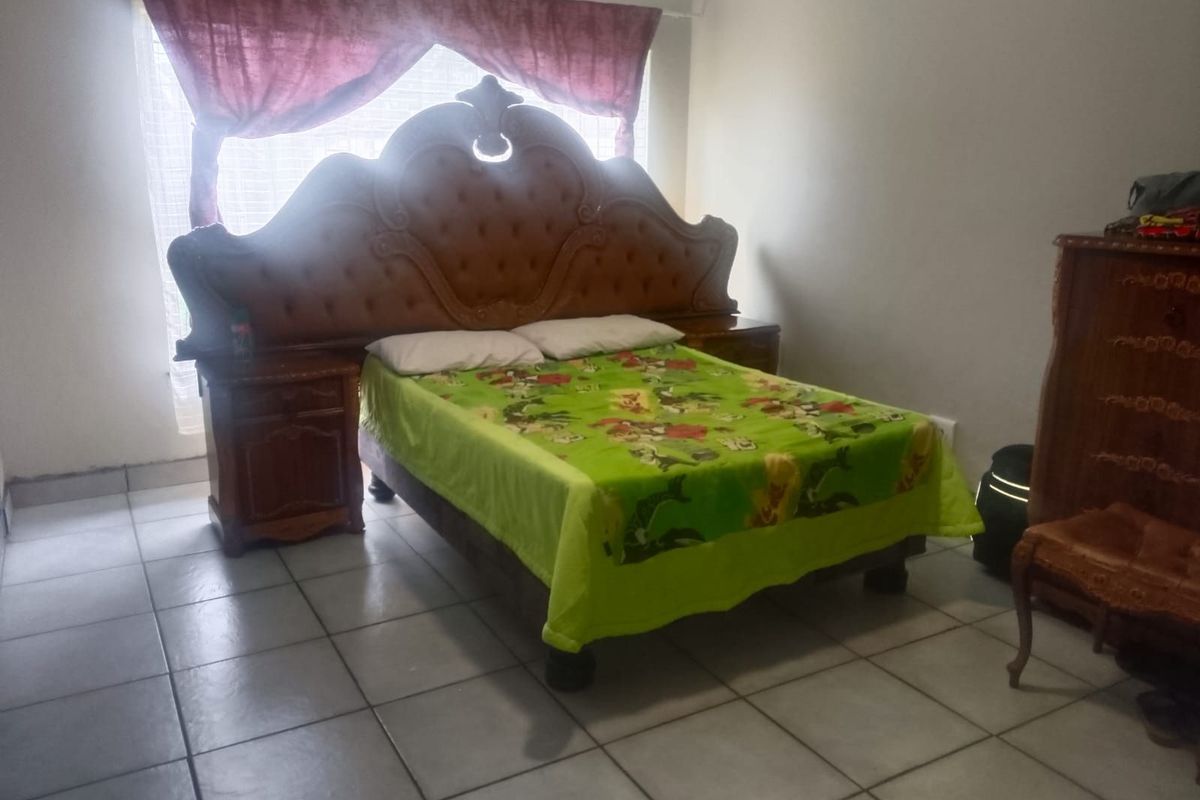 A bedroom featuring tiled flooring and a window with curtain fixtures.