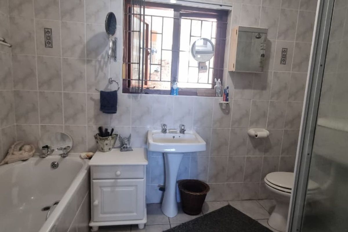 A functional bathroom featuring a bathtub, pedestal sink, toilet, and a separate shower enclosure with full-height wall tiling.