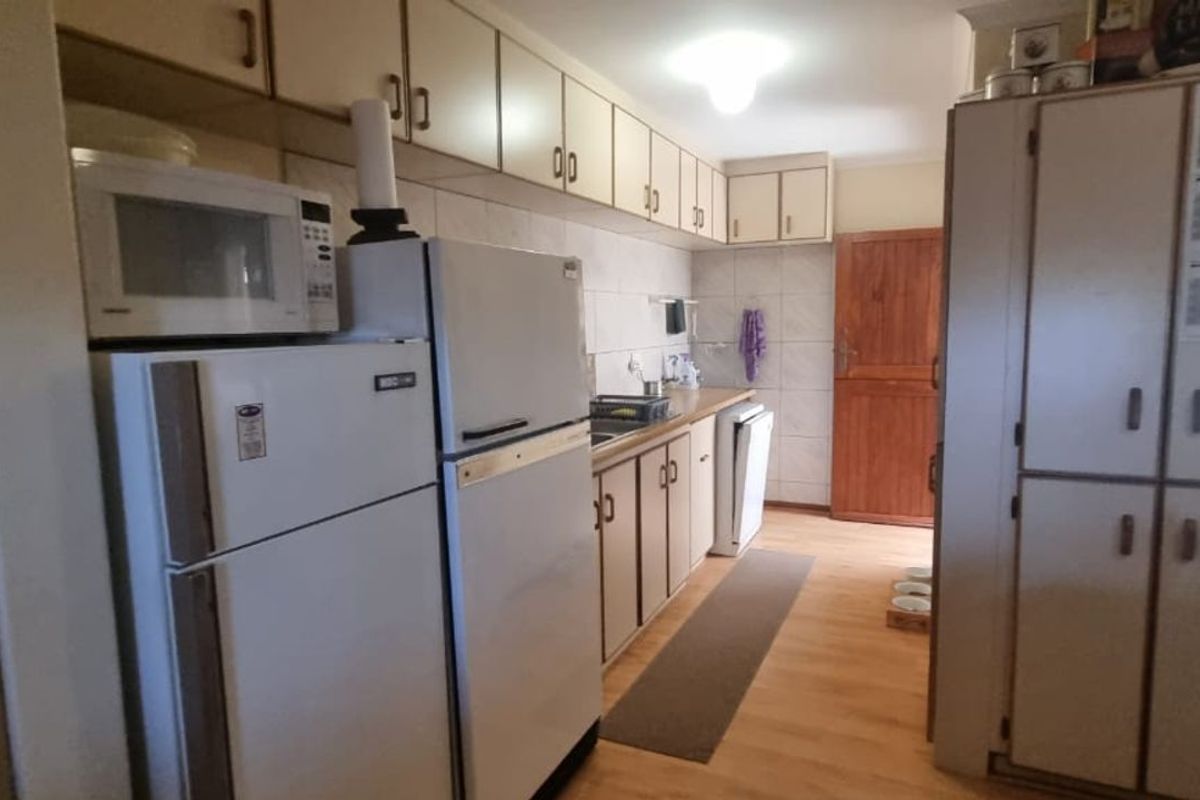 A functional kitchen featuring extensive built-in cabinetry, laminate countertops, and tiled splashbacks, offering a practical layout with ample storage space.