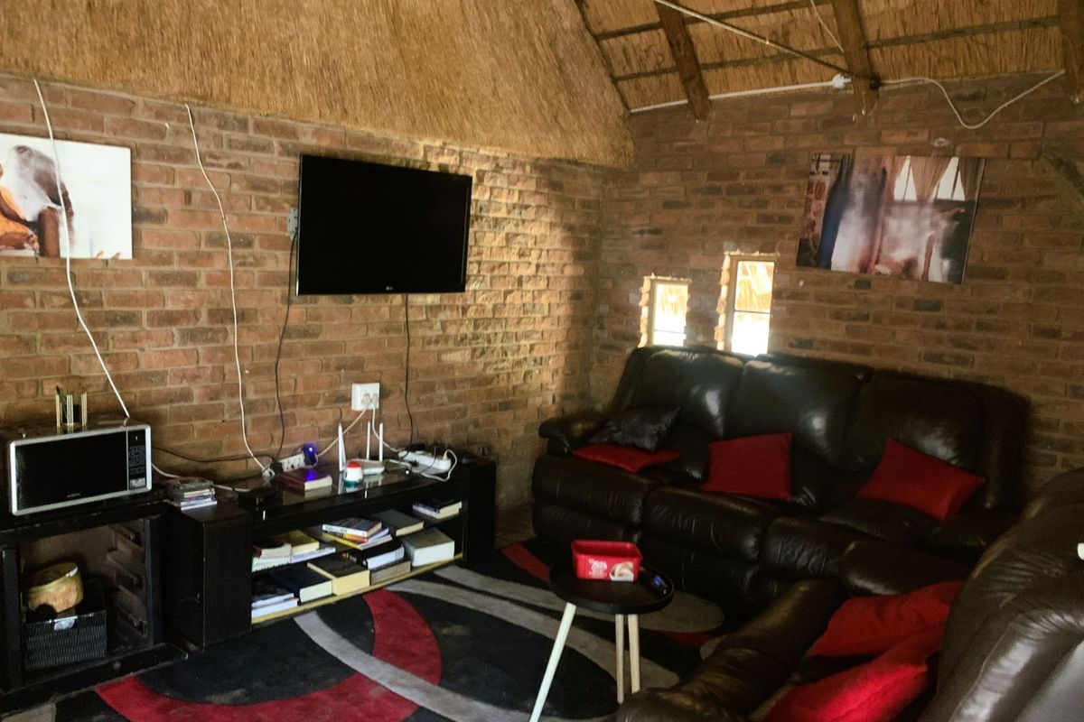 Rustic living room featuring exposed brick walls and a traditional thatched roof, creating a warm and character-filled interior space.