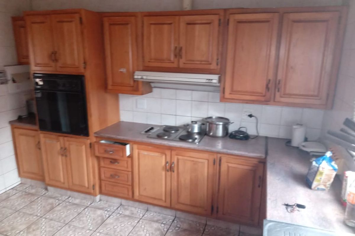 A functional kitchen featuring traditional timber cabinetry, built-in oven, integrated extractor fan, and tiled flooring with ample counter space.